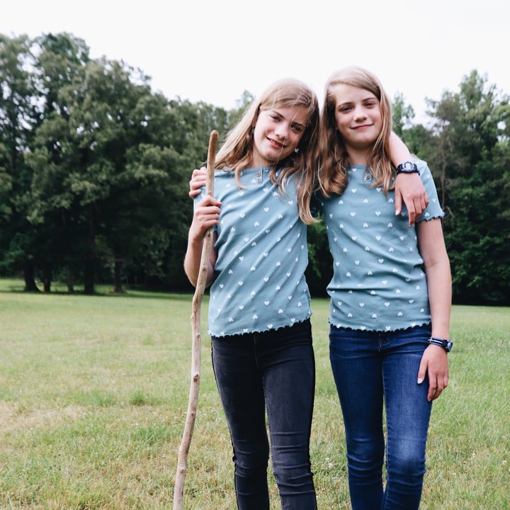 Two sisters arm in arm in a summer field